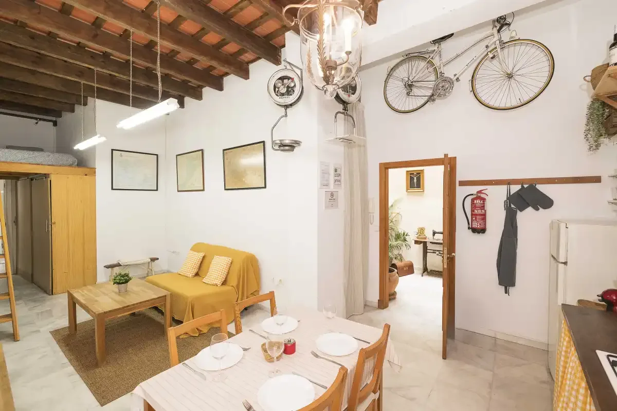 A bright living and dining area with seating, a table, and bicycles mounted on the wall.