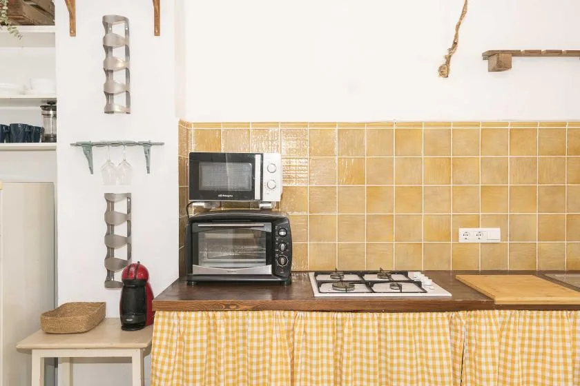 A kitchen counter with a microwave, countertop oven, and stovetop.