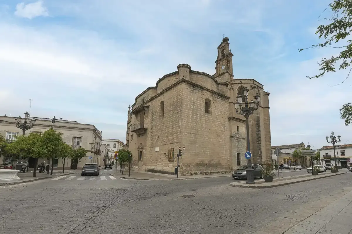 A large stone church stands beside a cobblestone street and open square.