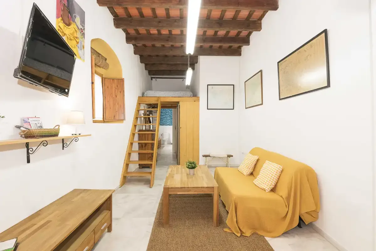 A bright living room with a mustard-colored sofa and a wooden coffee table.