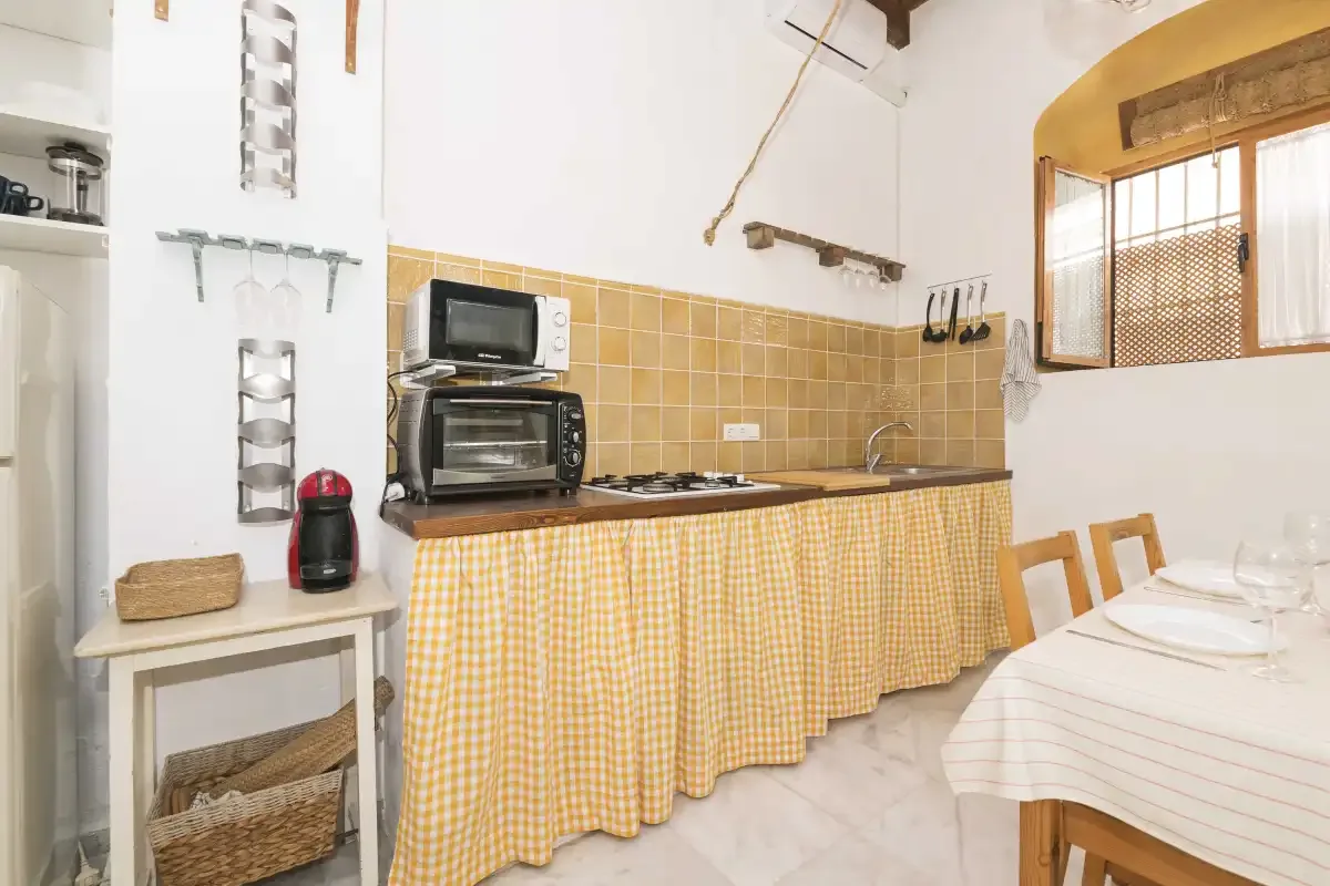A bright kitchen and dining area with a counter, small appliances, and a set table.