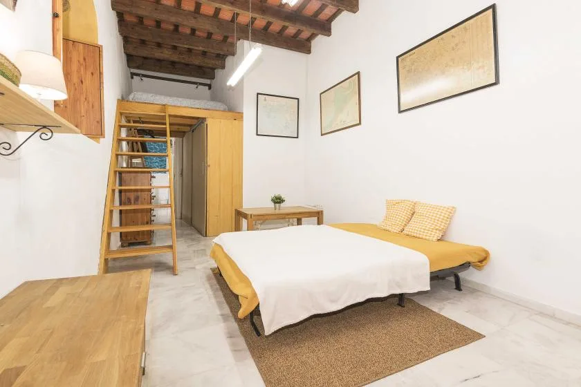 A bedroom with a bed, wooden ladder, and exposed ceiling beams.