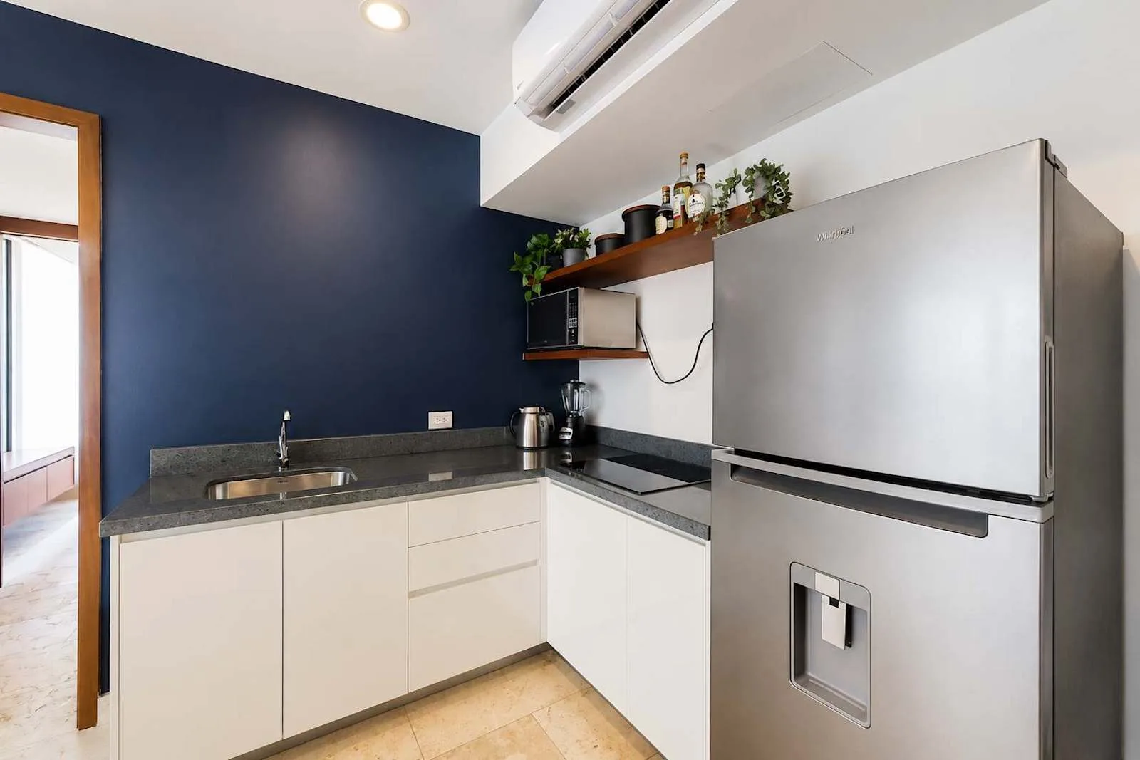 Una cocina compacta con gabinetes blancos, una encimera y un refrigerador.
