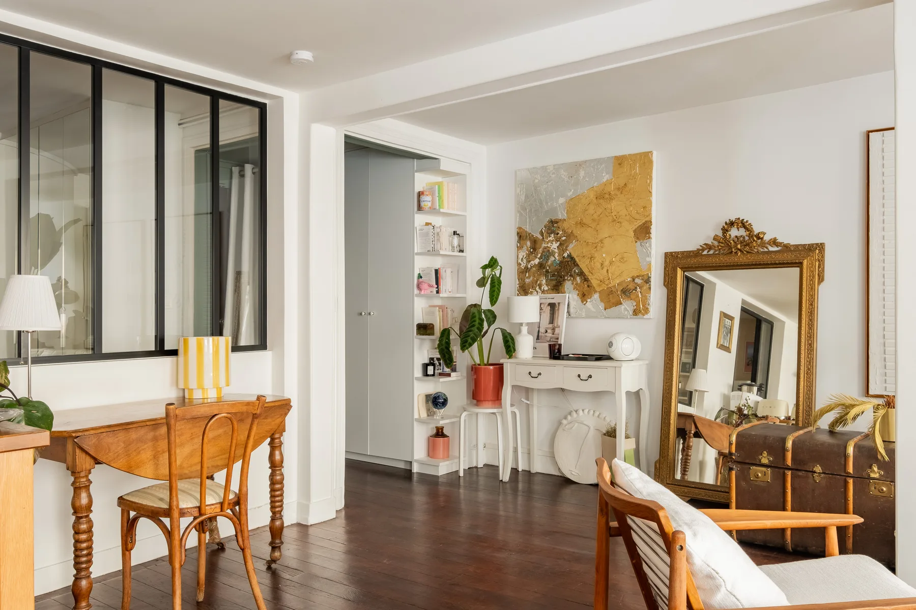 Una sala de estar luminosa con una mesa de madera, asientos y un espejo grande.