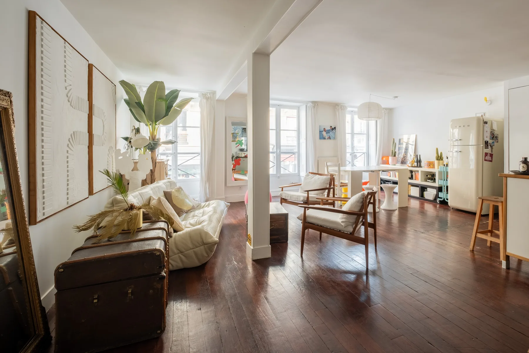 Una luminosa sala de estar con asientos, ventanas grandes y una mesa de comedor.
