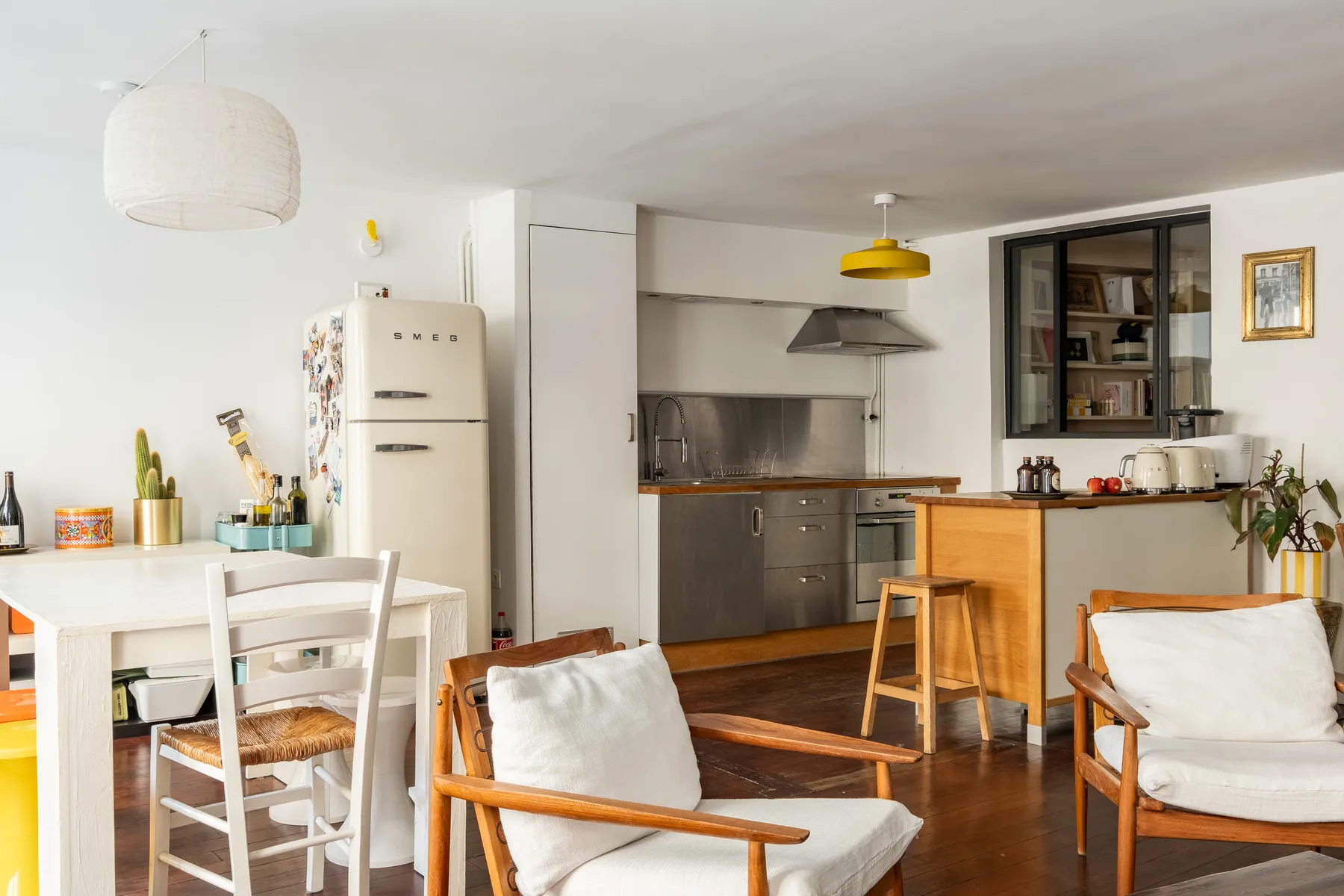 Una luminosa cocina y comedor con asientos de madera y una mesa blanca.