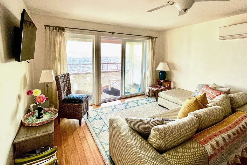 A bright living room with seating beside large glass doors opening to a balcony.