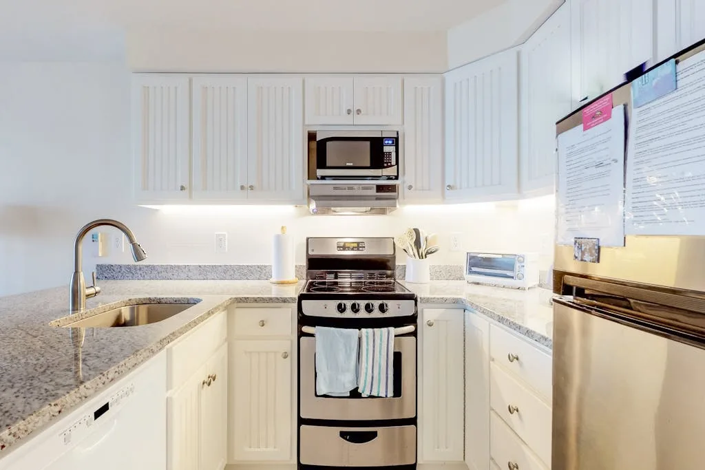 A bright kitchen with white cabinets, granite counters, and a stainless steel range.