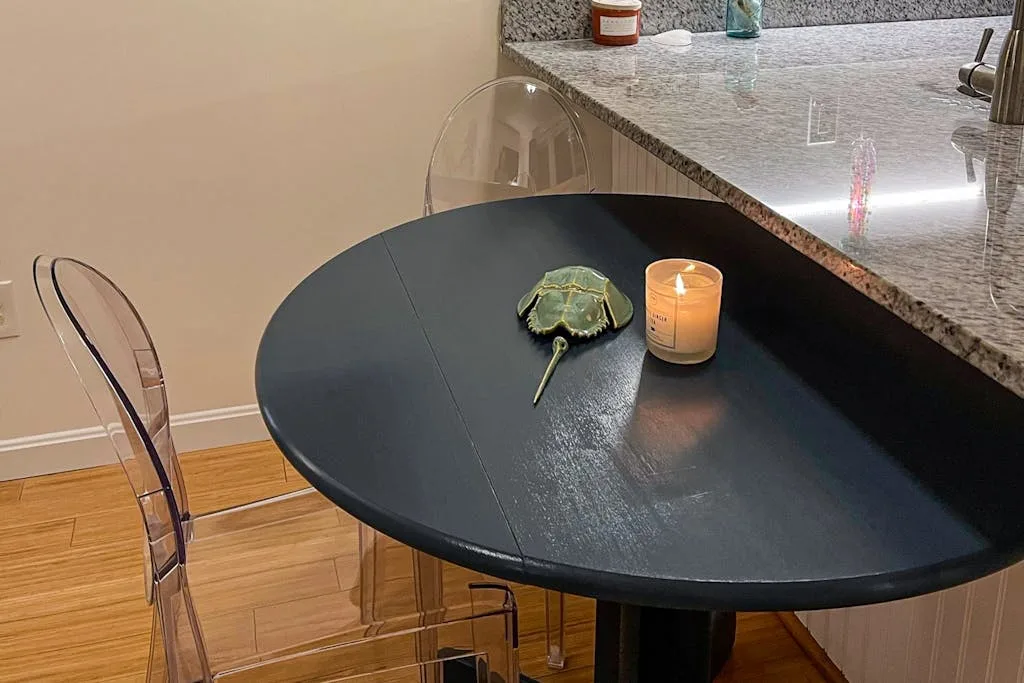 A black dining table with clear seating, a candle, and a small decorative turtle.