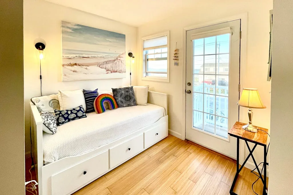 A bright room with a white daybed beneath a beach landscape painting.