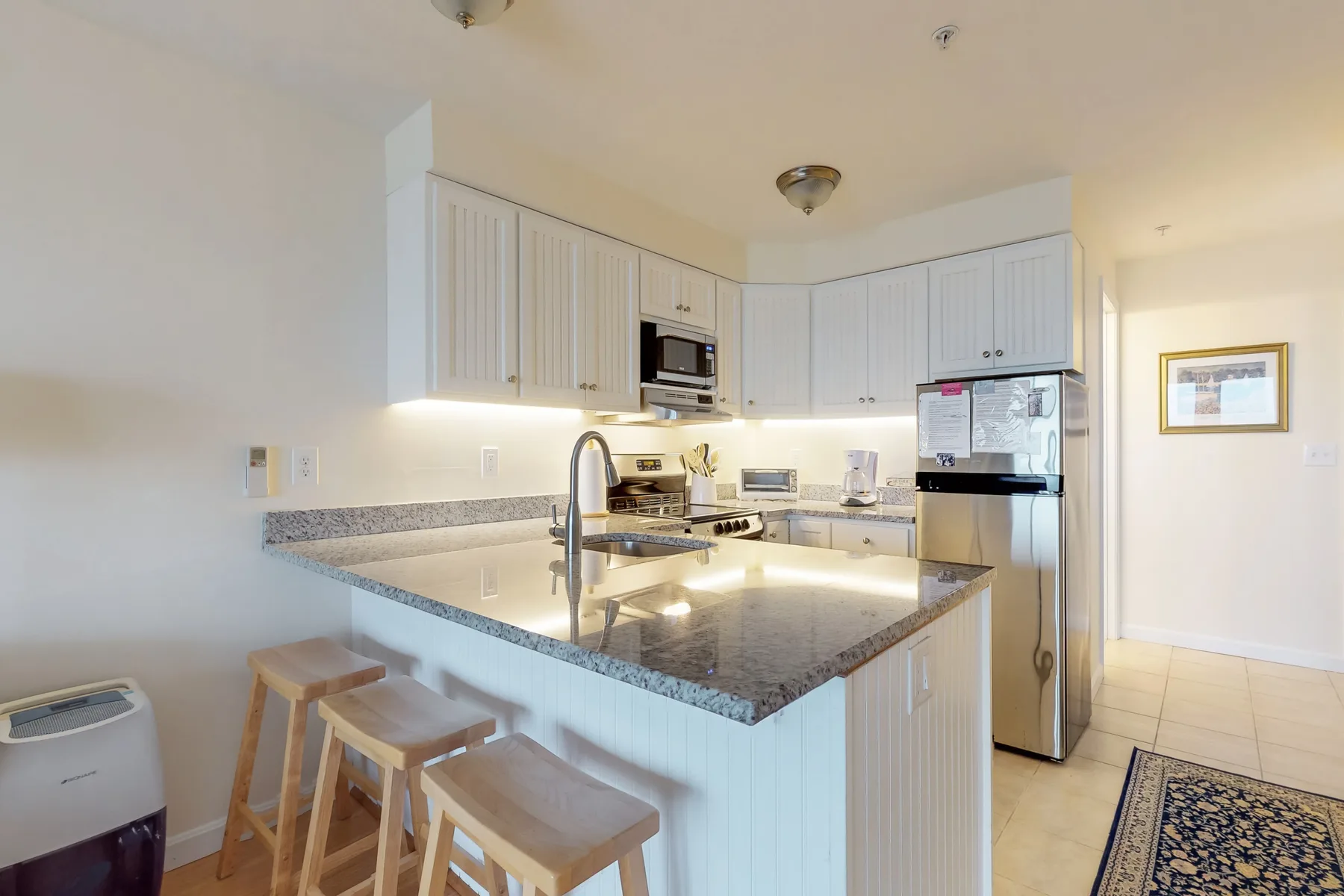 A bright kitchen with white cabinets, a central island, and bar seating.
