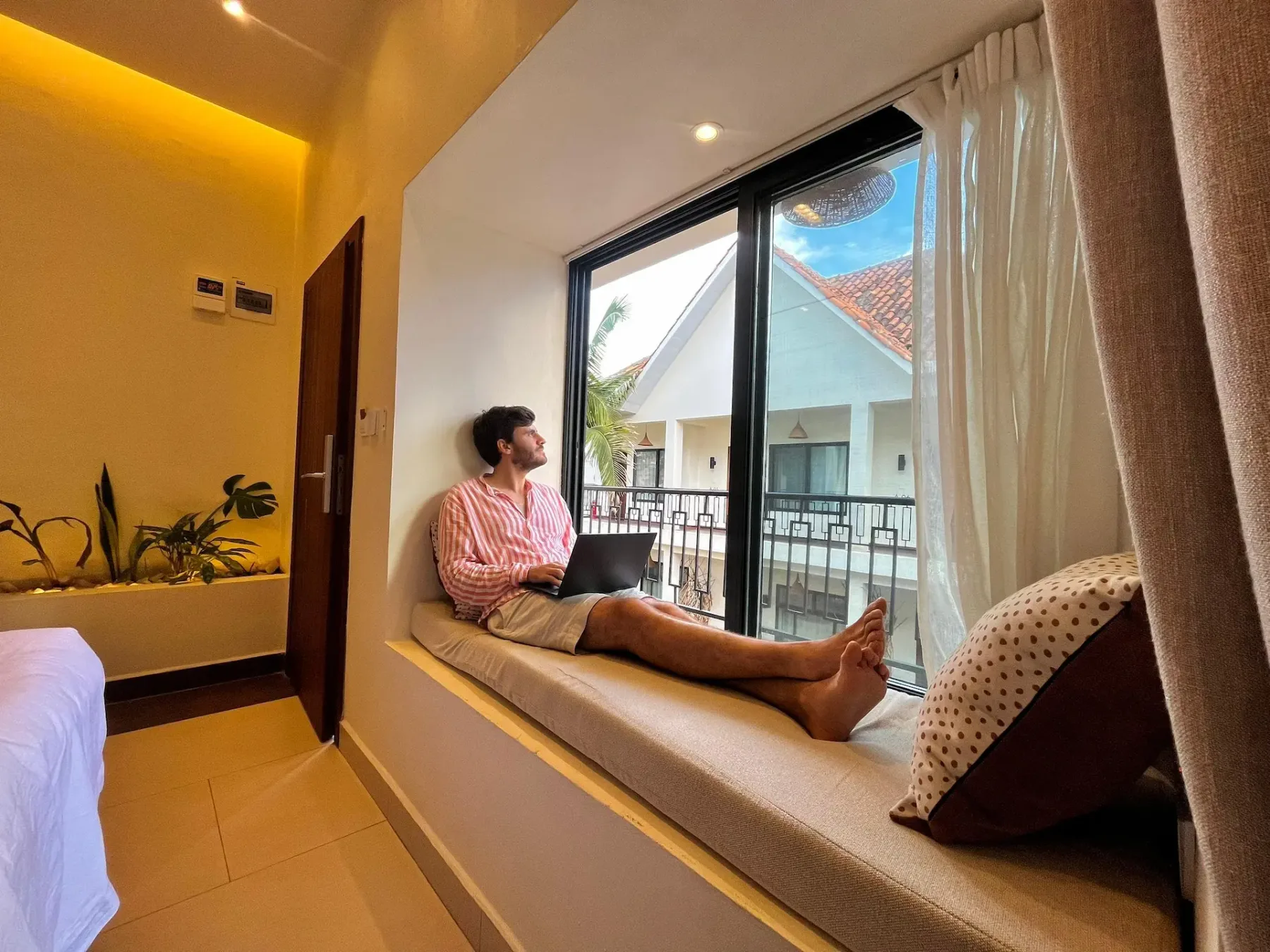 Huésped que utiliza un asiento junto a la ventana de una habitación como espacio de trabajo