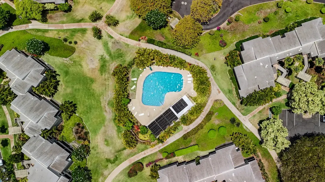 An aerial view of a swimming pool surrounded by landscaped grounds and buildings.