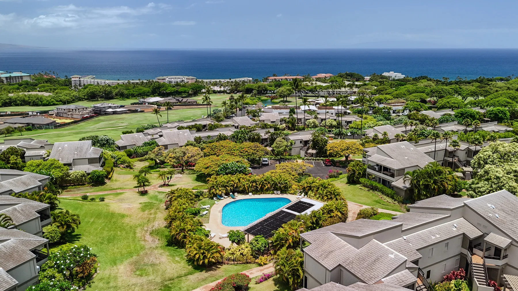 Aerial view of a landscaped resort with a swimming pool and ocean beyond.