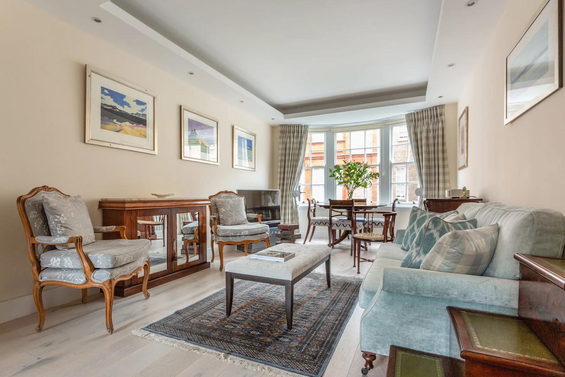 A bright living room with seating, a coffee table, and a dining area by the windows.