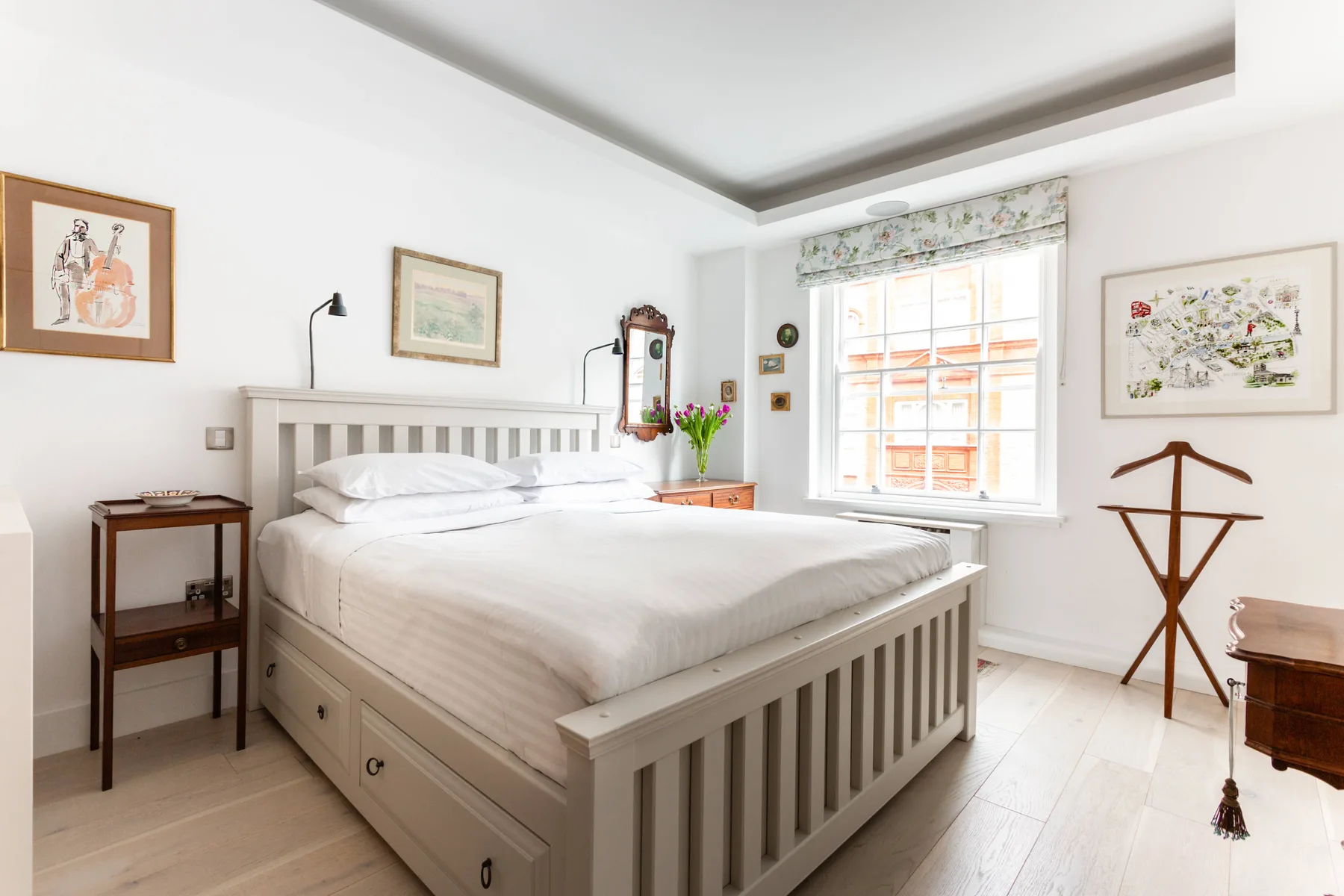 A bright bedroom features a large white bed beside a window.