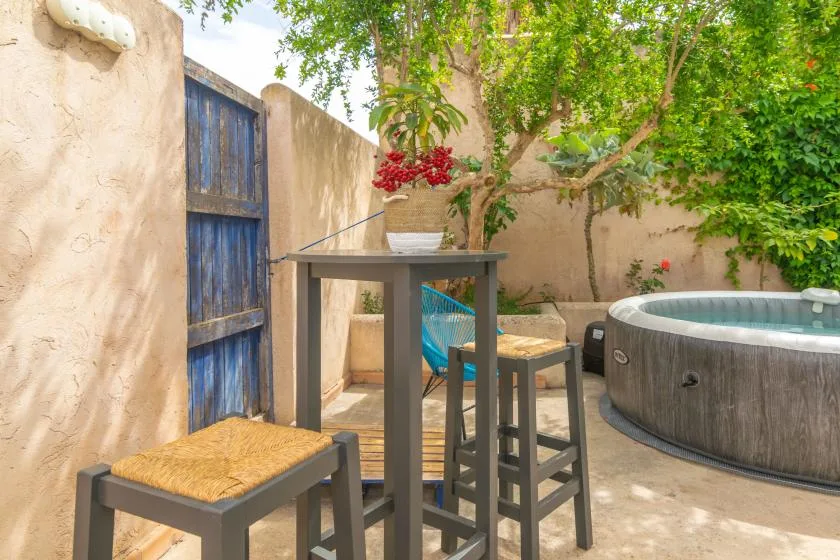 A small outdoor patio with a table, seating, and a round hot tub.