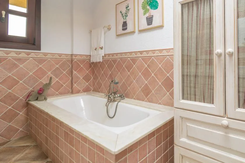 A bathroom with a bathtub, tiled walls, and a cabinet.