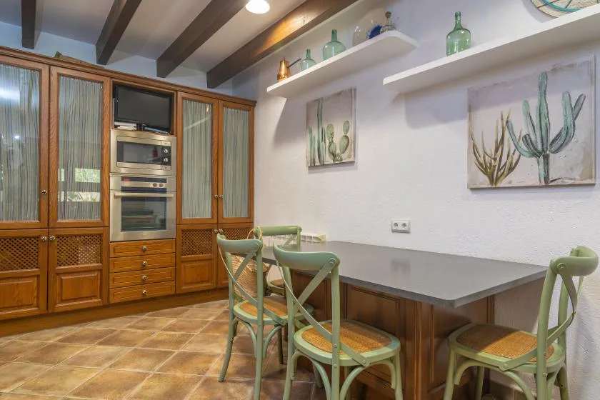 A dining area with green seating beside built-in wooden cabinets and wall art.