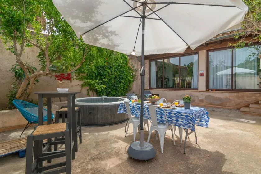 An outdoor dining area with a table beneath a large patio umbrella.
