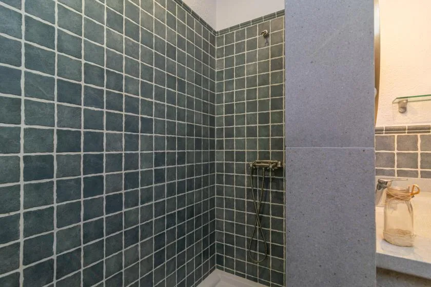 A tiled shower area with a wall-mounted shower fixture.