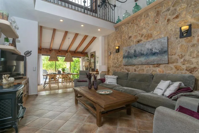 A living room with seating and a wooden coffee table beside a stone wall.