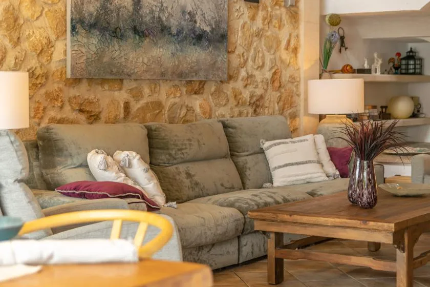 A living room with a large sofa, wooden coffee table, and stone-patterned wall.