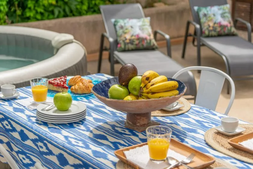 An outdoor dining table with fruit and drinks beside a seating area.