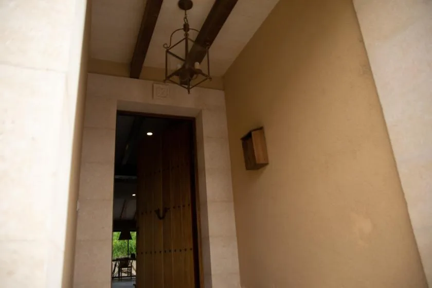 An interior hallway leads to a wooden doorway beneath exposed ceiling beams.