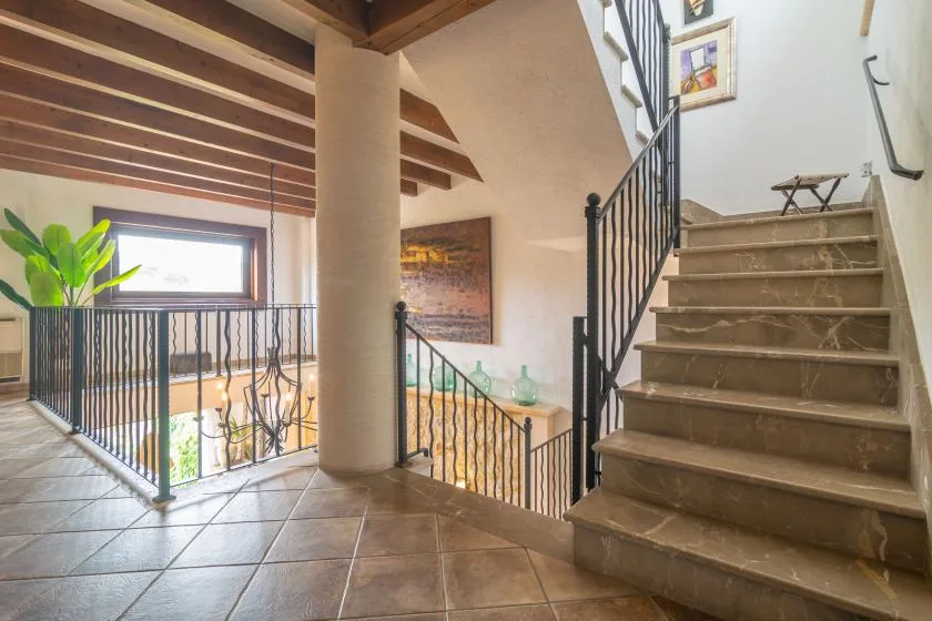 A tiled staircase and landing with dark railings and a tall central column.