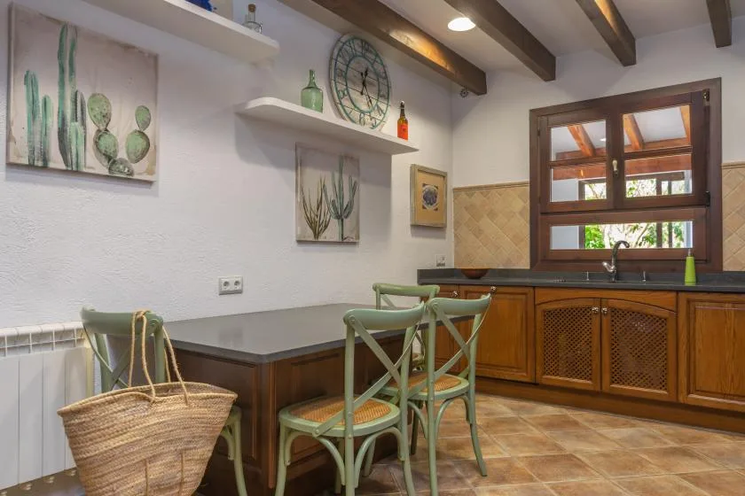 A kitchen dining area with green chairs beside a wooden counter and window.
