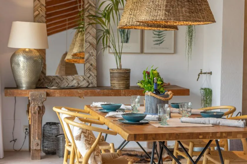 A dining area with a wooden table, woven chairs, and a large pendant light.