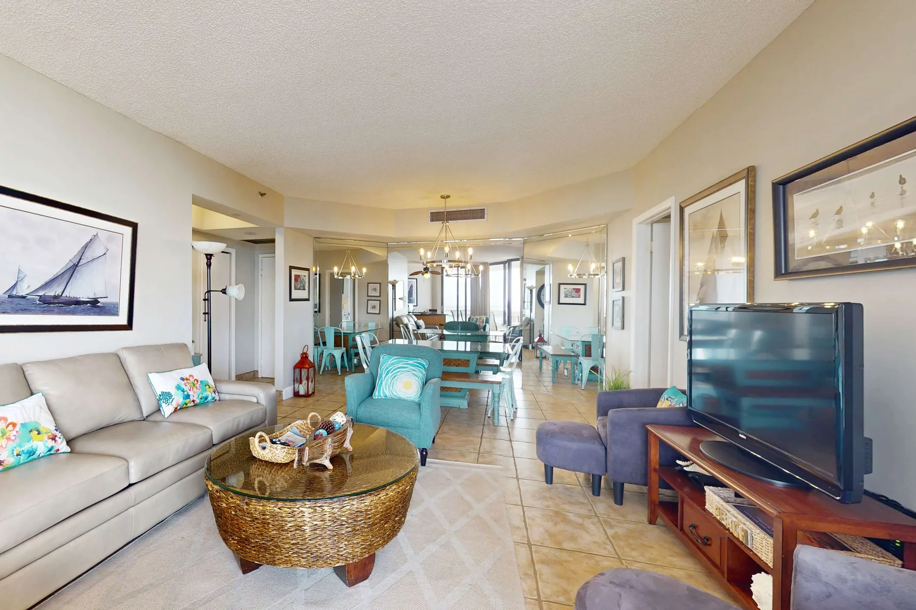 A bright living room with seating, a television, and a dining area beyond.