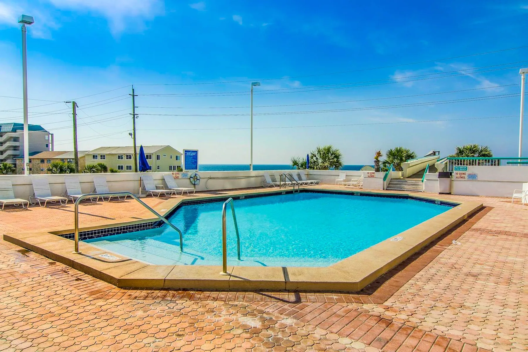 Una piscina al aire libre con asientos y vistas al mar.