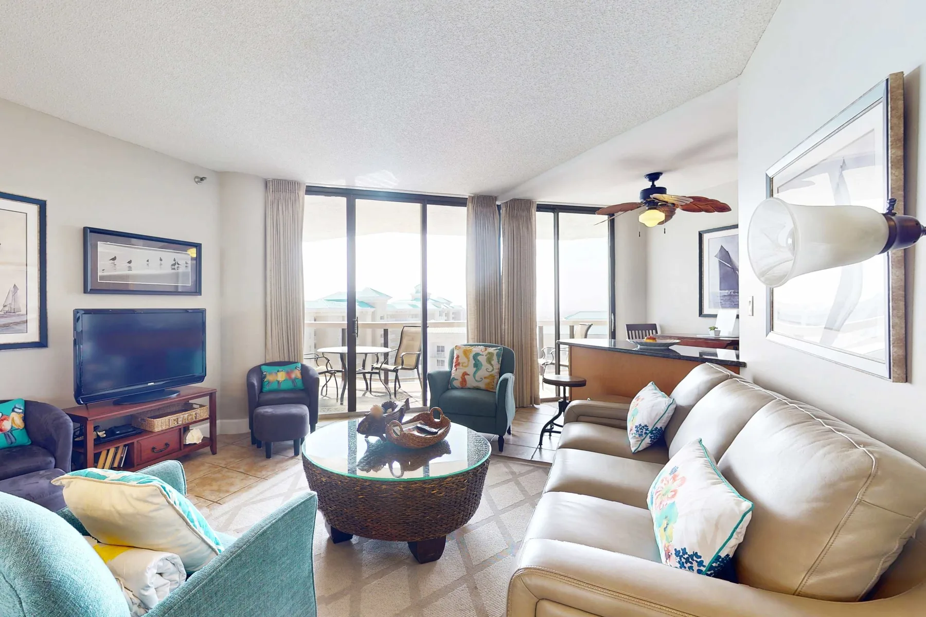 A bright living room with seating arranged around a coffee table and large windows.
