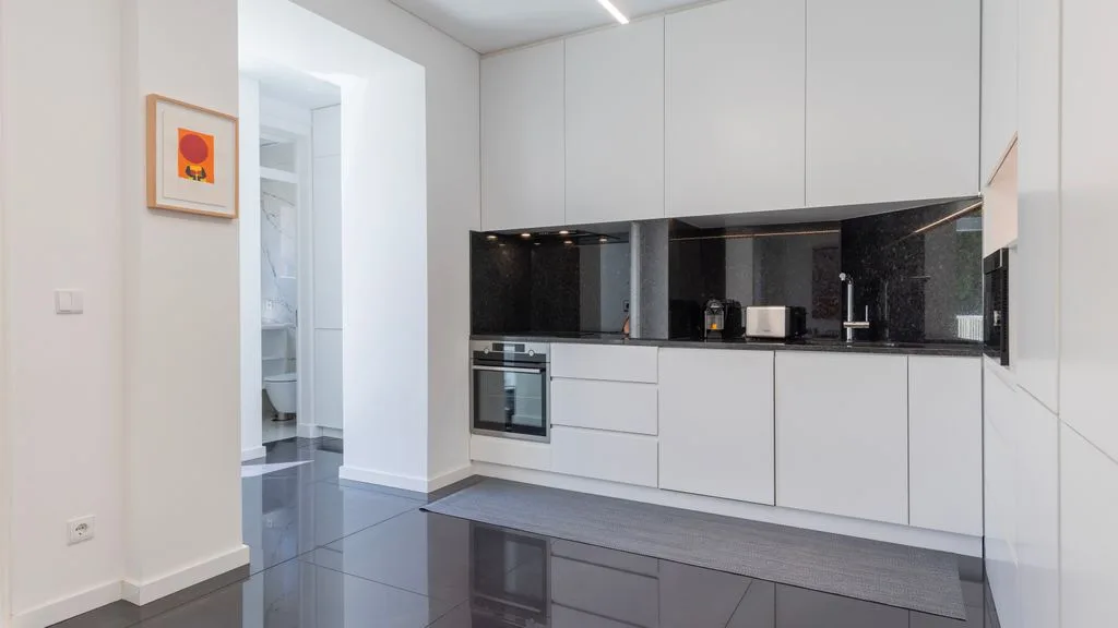 Una cocina moderna con armarios blancos y una encimera oscura.