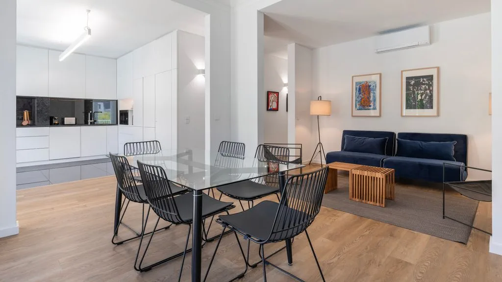 Una sala de estar y comedor diáfana cuenta con una mesa de comedor y asientos oscuros.