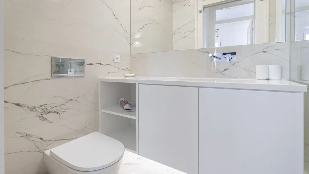 Un baño luminoso con lavabo, mueble blanco e inodoro.