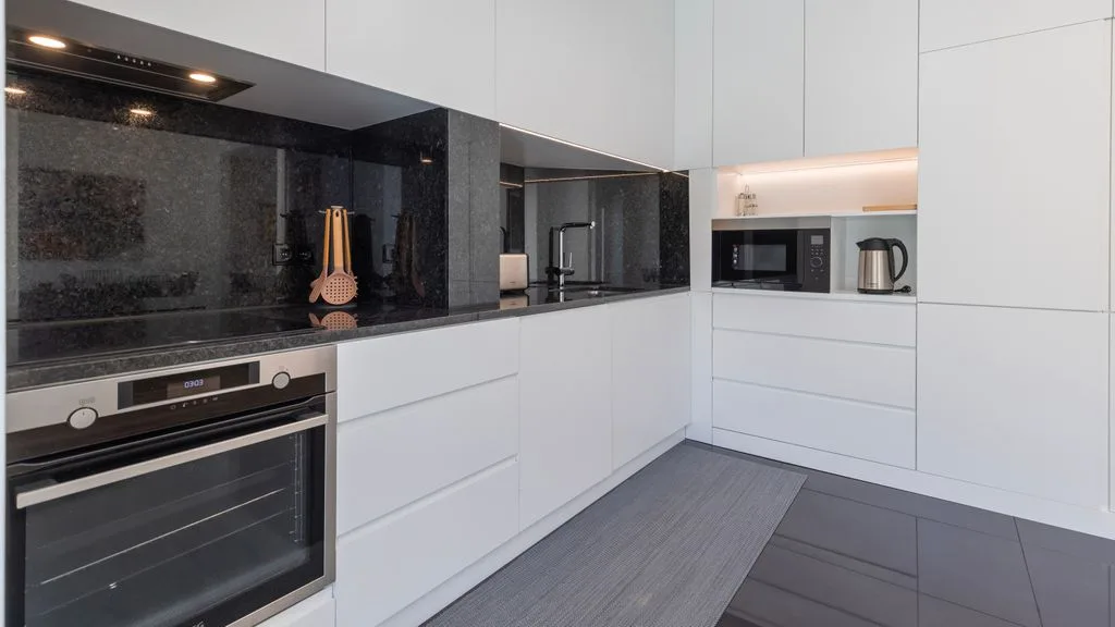 Una cocina moderna con gabinetes blancos y electrodomésticos integrados.