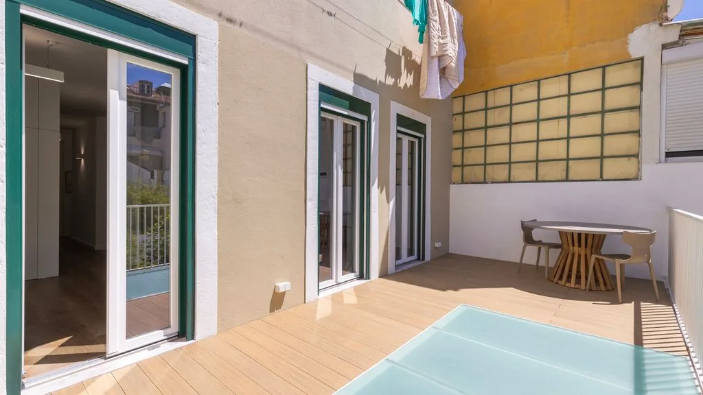 Una terraza soleada con una pequeña piscina, puertas de vidrio y asientos al aire libre.
