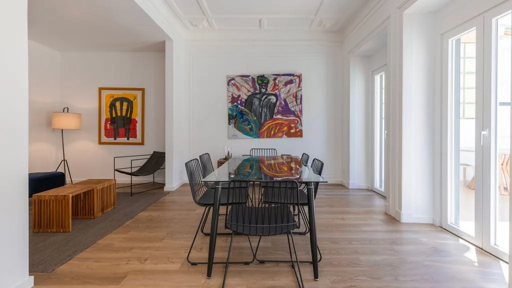 Un comedor luminoso con una mesa y una obra de arte colorida en la pared.