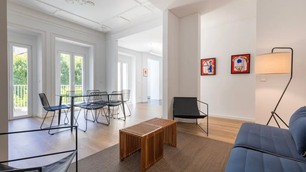 Una luminosa sala de estar y comedor con asientos, una mesa de centro y ventanales.