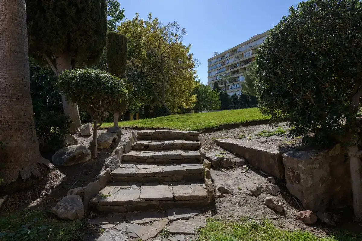Stone steps lead through a landscaped outdoor area toward a grassy lawn.