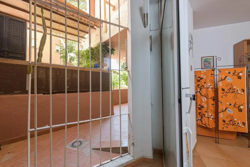 A gated patio entrance opens onto a tiled courtyard with potted plants.