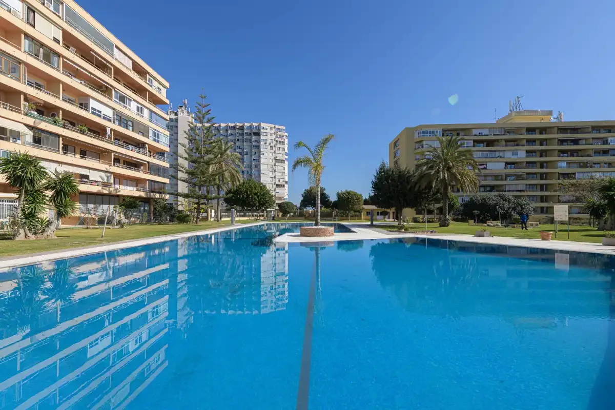 An outdoor swimming pool sits among several apartment buildings.