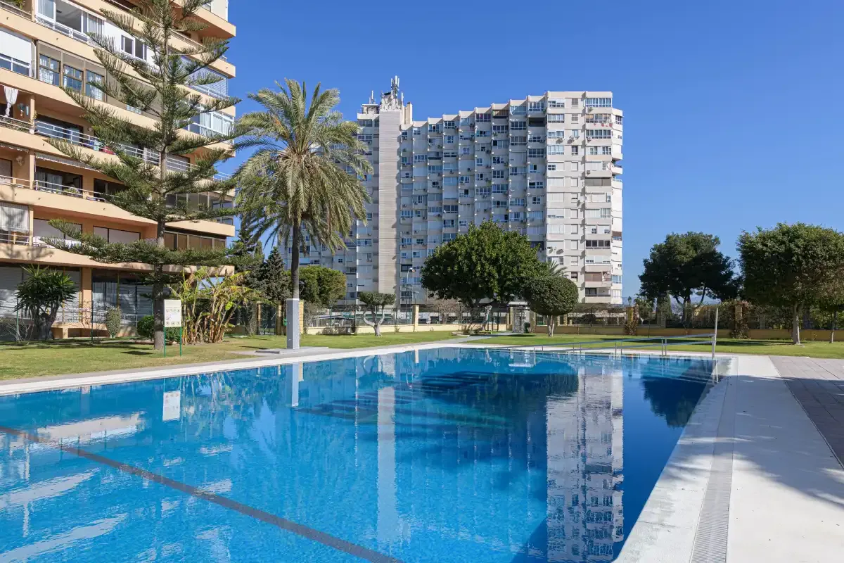 Outdoor swimming pool beside apartment buildings on a sunny day.