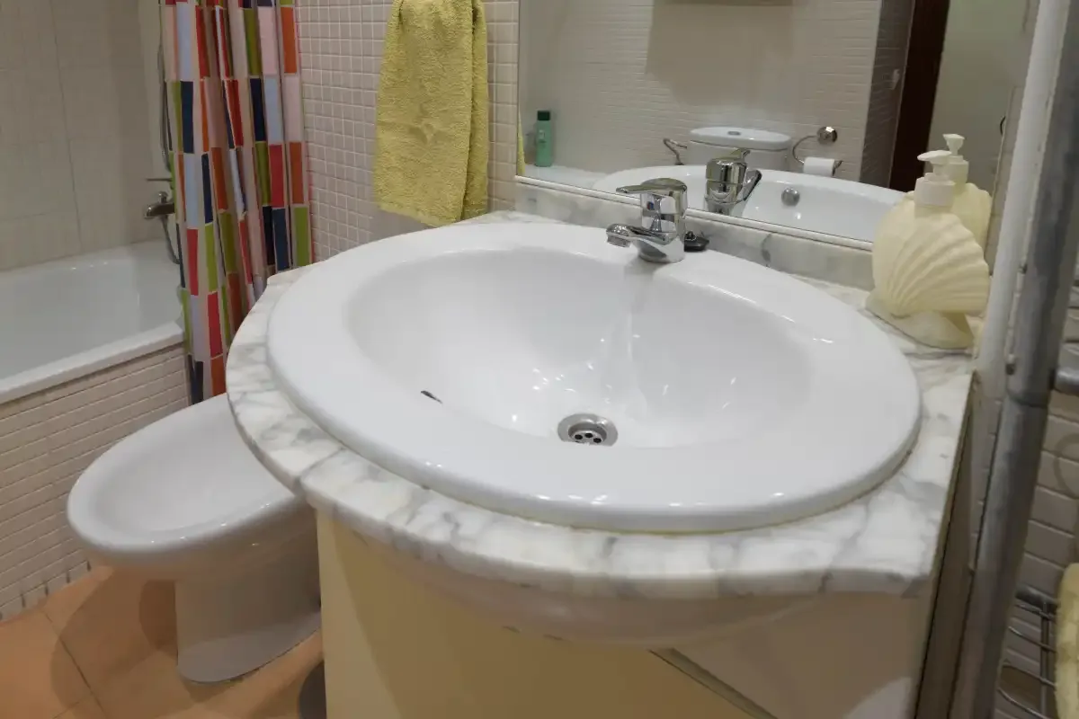 A bathroom vanity with an oval sink, with a bathtub visible beside it.