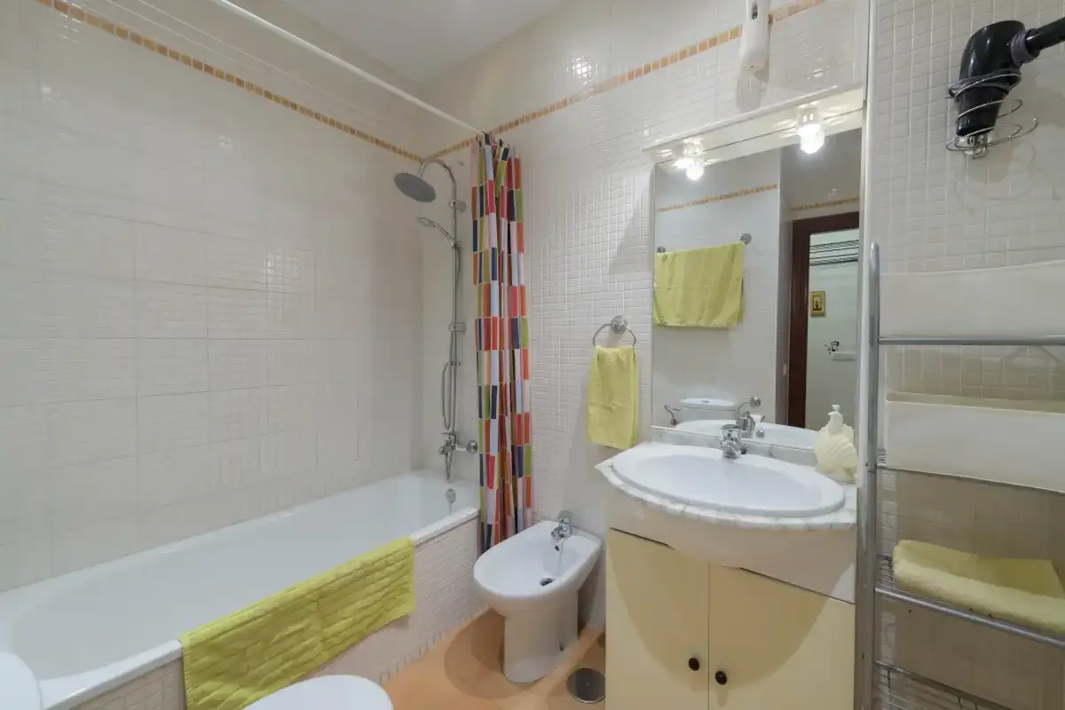 A tiled bathroom with a bathtub, sink, and colorful shower curtain.