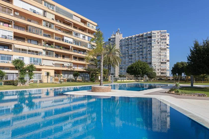 A swimming pool beside apartment buildings and palm trees.
