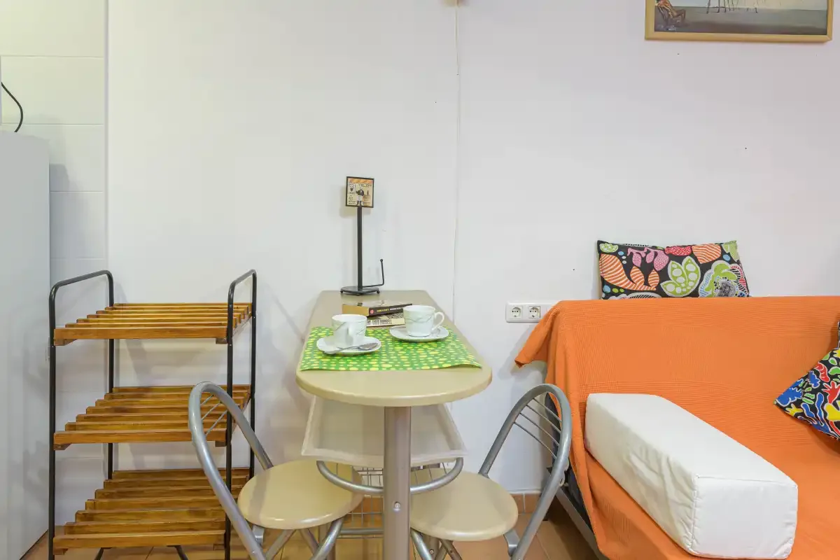 A compact dining area with a small table beside orange-covered seating.